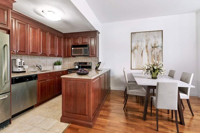 kitchen featuring tasteful backsplash, stainless steel appliances, sink, and light stone counters