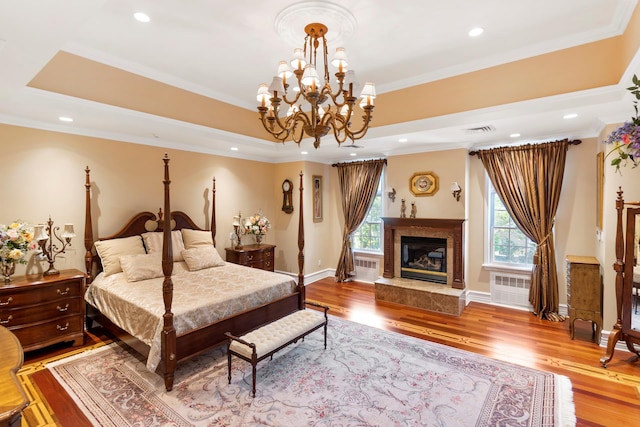 bedroom with wood finished floors, a raised ceiling, visible vents, and crown molding