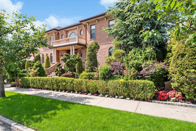 mediterranean / spanish home with a balcony, a front yard, and brick siding