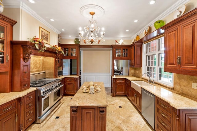 kitchen with a kitchen island, appliances with stainless steel finishes, decorative light fixtures, sink, and light stone counters