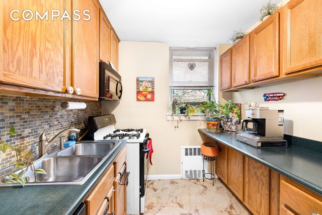 kitchen with radiator, a sink, white gas range oven, black microwave, and marble finish floor