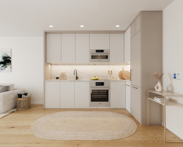 kitchen featuring white cabinets, backsplash, sink, and stainless steel oven