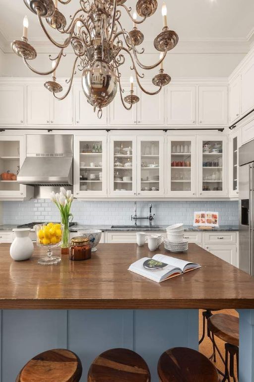 kitchen featuring white cabinetry, wall chimney exhaust hood, butcher block countertops, and a breakfast bar area