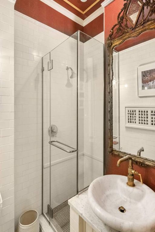 bathroom featuring sink, crown molding, and a shower with door