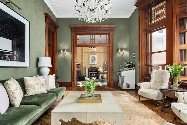 living room featuring a tiled fireplace, parquet floors, a notable chandelier, and crown molding