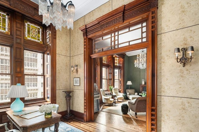 sitting room with hardwood / wood-style flooring, crown molding, a high ceiling, and a chandelier