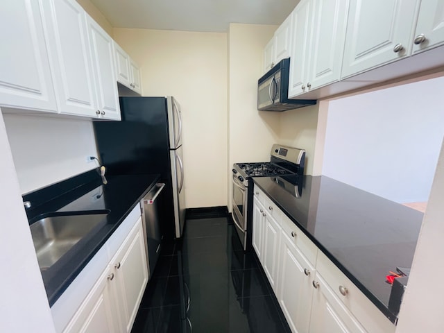 kitchen with appliances with stainless steel finishes, dark tile patterned flooring, sink, and white cabinets