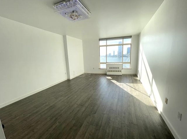 unfurnished living room featuring dark wood-type flooring and baseboards