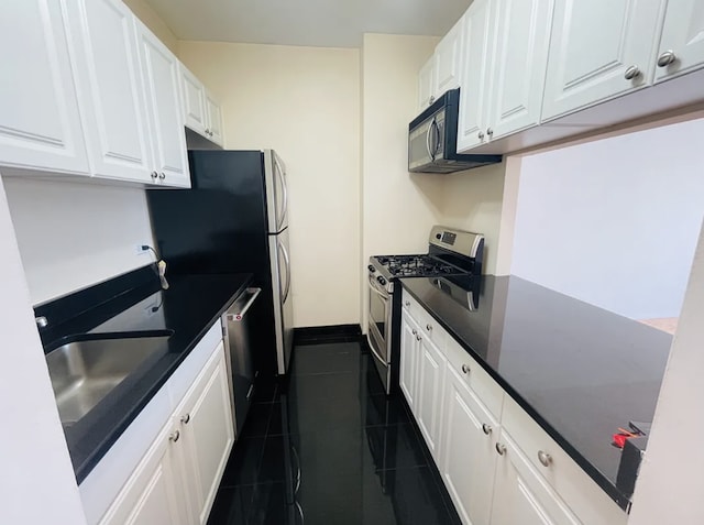 kitchen with appliances with stainless steel finishes, white cabinets, and dark countertops