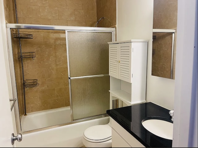 bathroom with bath / shower combo with glass door, toilet, and vanity