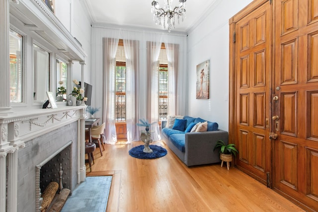 living area with a fireplace with flush hearth, crown molding, and light wood-style flooring