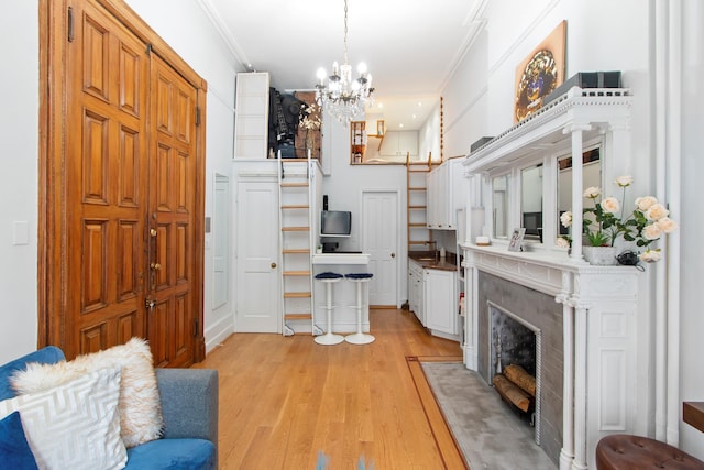 living room with a chandelier, crown molding, light wood-type flooring, and a premium fireplace