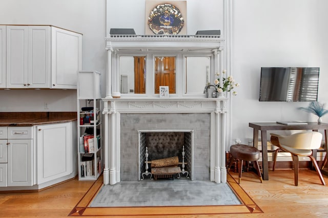 living room featuring a fireplace with flush hearth and light wood-style flooring