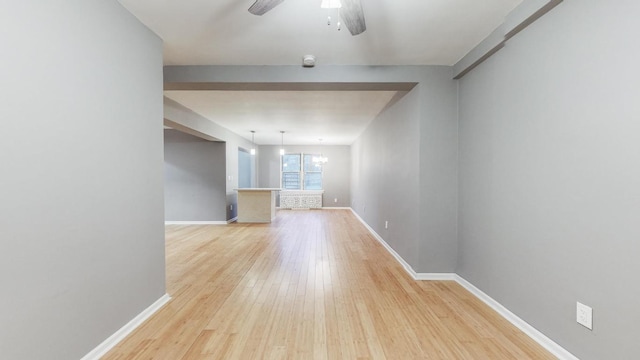 unfurnished living room with ceiling fan with notable chandelier and light hardwood / wood-style flooring