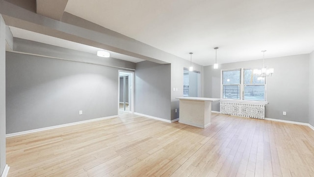 spare room featuring a chandelier and light hardwood / wood-style floors