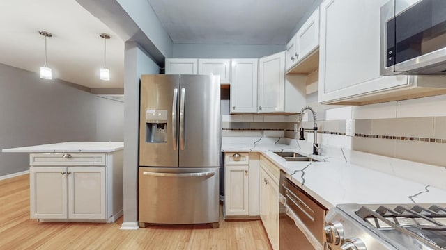 kitchen featuring pendant lighting, sink, light hardwood / wood-style flooring, white cabinetry, and stainless steel appliances