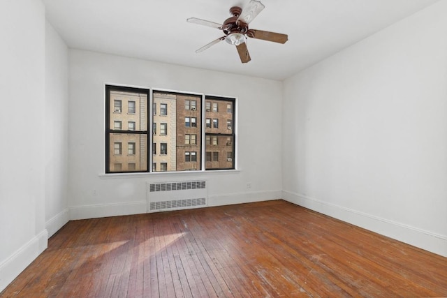 spare room featuring ceiling fan, radiator, and hardwood / wood-style floors