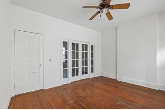 empty room with ceiling fan and dark hardwood / wood-style flooring