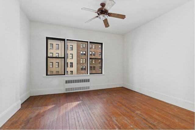 empty room featuring radiator, hardwood / wood-style floors, and ceiling fan