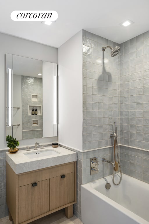 bathroom with vanity, tiled shower / bath combo, and tile walls