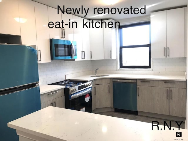 kitchen with stainless steel gas stove, black dishwasher, sink, decorative backsplash, and fridge