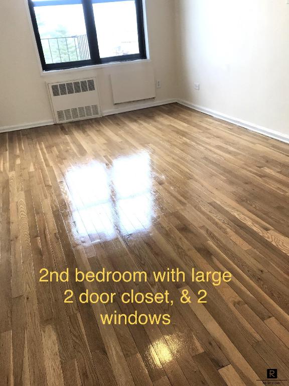 unfurnished room with radiator and wood-type flooring