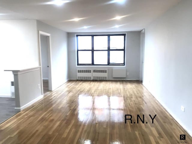 spare room featuring radiator and hardwood / wood-style floors