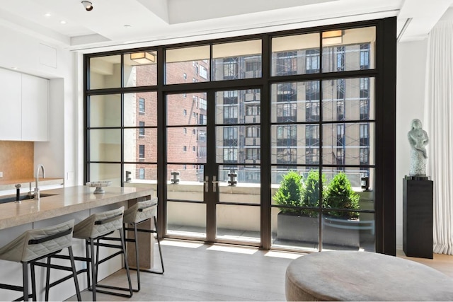 interior space featuring expansive windows, sink, light hardwood / wood-style flooring, and french doors