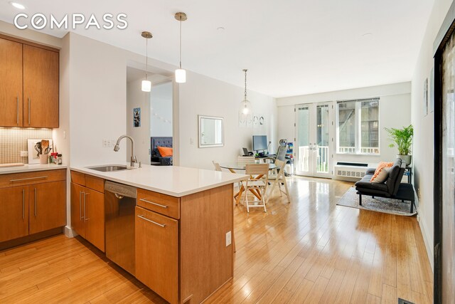 kitchen featuring light wood-style flooring, a sink, stainless steel dishwasher, open floor plan, and a peninsula