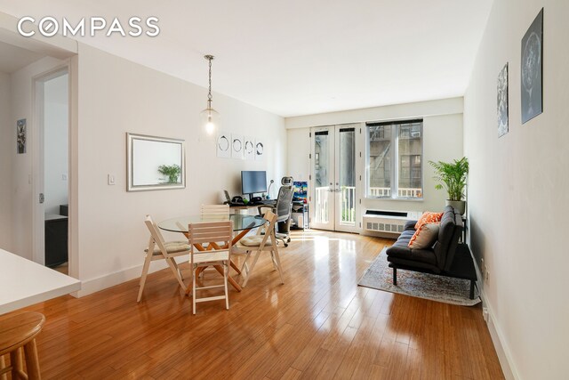 dining room with french doors, baseboards, radiator heating unit, and light wood finished floors