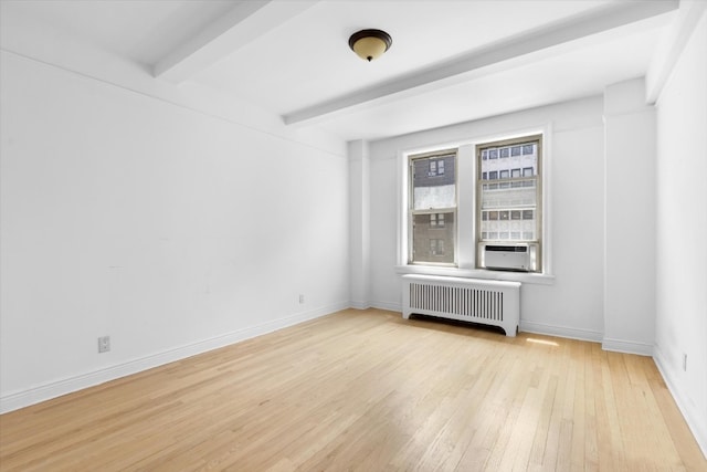 unfurnished room featuring light hardwood / wood-style floors, radiator, and beam ceiling