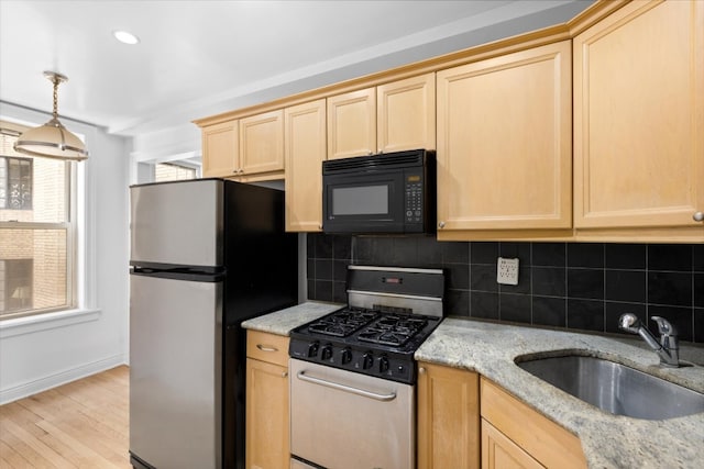 kitchen with decorative backsplash, sink, light hardwood / wood-style flooring, light stone countertops, and stainless steel appliances