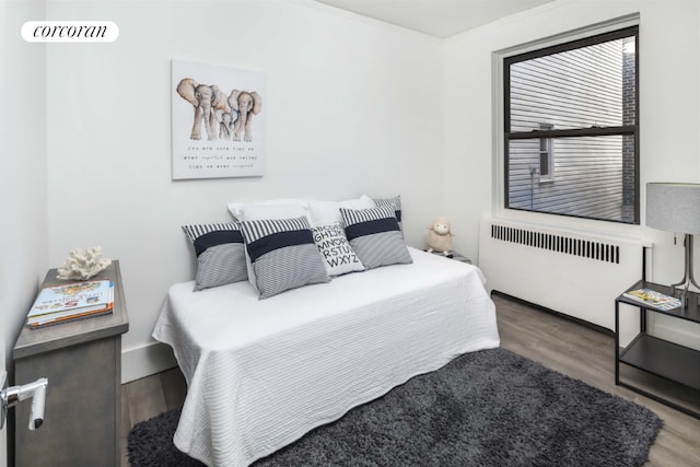 bedroom featuring radiator heating unit and wood-type flooring