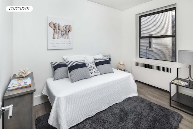 bedroom with radiator and wood finished floors