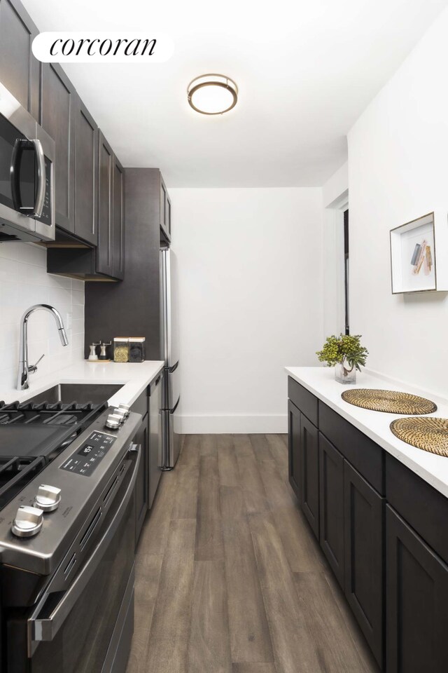 kitchen with dark brown cabinetry, decorative backsplash, stainless steel appliances, and dark hardwood / wood-style floors