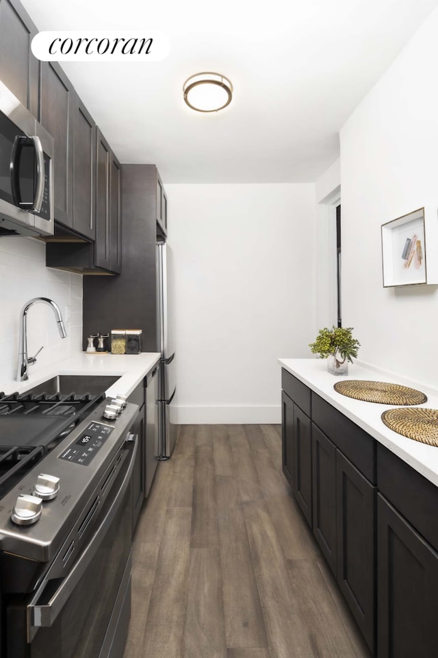 kitchen featuring light countertops, appliances with stainless steel finishes, dark wood-type flooring, and decorative backsplash