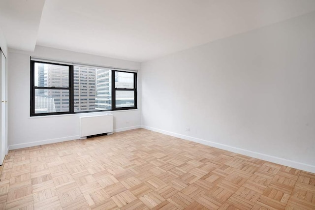 unfurnished room featuring radiator heating unit and light parquet floors