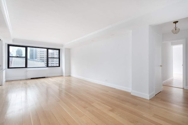 spare room featuring radiator heating unit and light hardwood / wood-style flooring