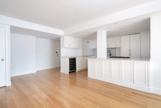 unfurnished living room featuring beverage cooler, sink, and light hardwood / wood-style flooring