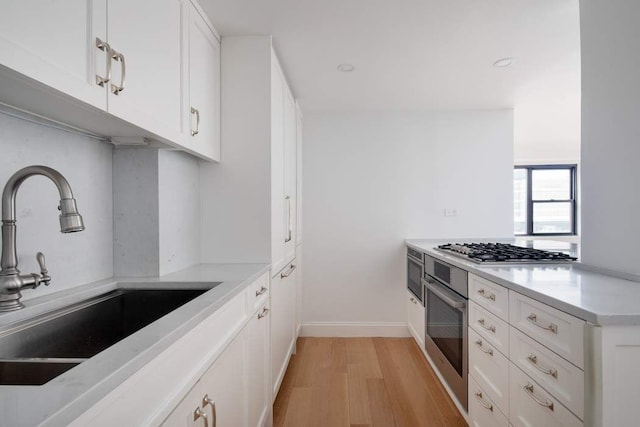 kitchen featuring white cabinetry, sink, light hardwood / wood-style flooring, and stainless steel appliances