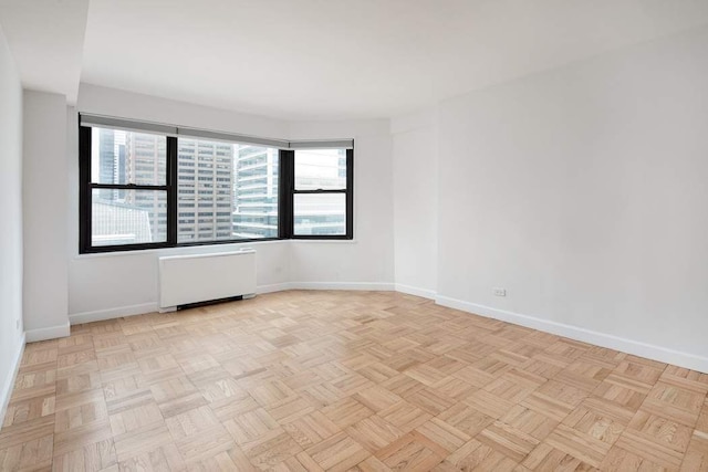 unfurnished room with radiator heating unit and light parquet flooring