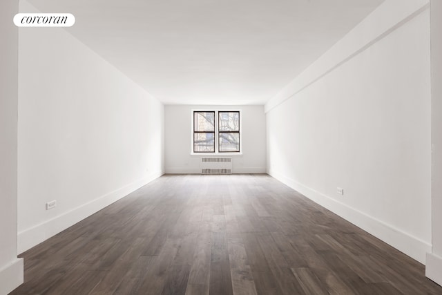 empty room featuring baseboards, dark wood-style flooring, visible vents, and radiator