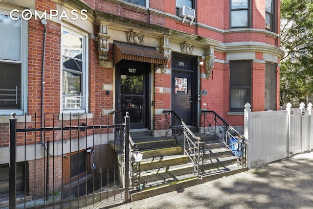 property entrance featuring brick siding, cooling unit, and fence