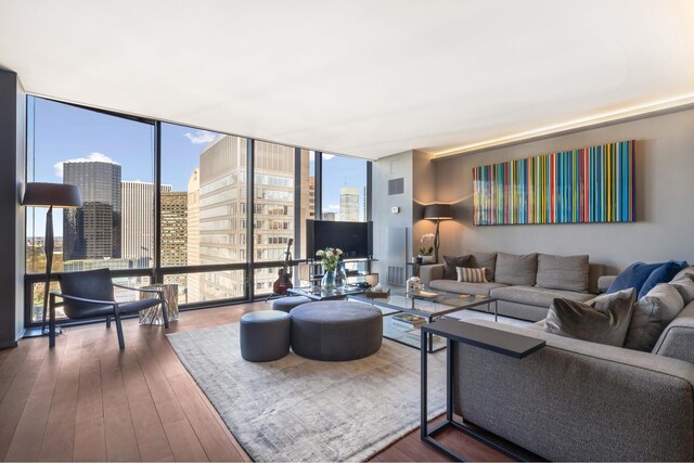 living room featuring wood-type flooring, floor to ceiling windows, and plenty of natural light