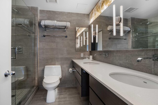 bathroom with tile walls, an enclosed shower, vanity, and toilet