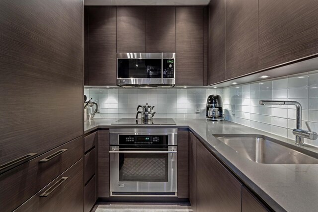 kitchen featuring appliances with stainless steel finishes, sink, dark brown cabinetry, and decorative backsplash