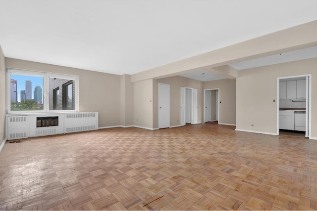 unfurnished living room with radiator heating unit and light parquet flooring