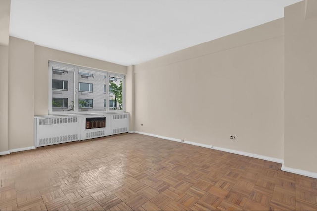 unfurnished living room featuring parquet flooring and radiator heating unit