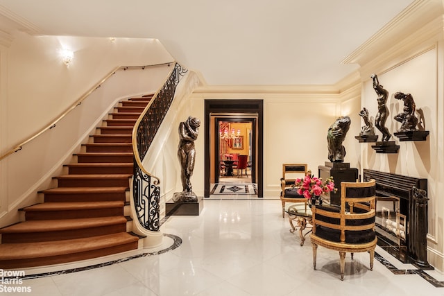 stairs with crown molding and a fireplace