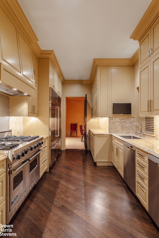 11 E 74th St, New York City, NY 10021 - kitchen with high quality appliances, cream cabinetry, dark wood-type flooring, tasteful backsplash, and crown molding